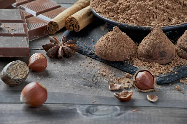 Farklı türde çikolata, kakao tozu, fındık ve diğer baharatlar. Ev yapımı trüf mantarı yapmak için gerekli malzemeler.