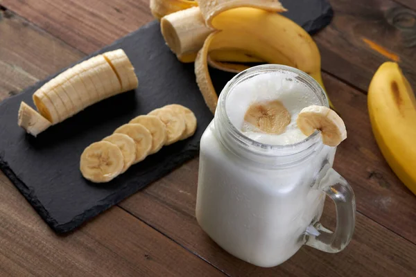 Tahta bir masada dilimlenmiş muzlu tatlı muzlu smoothie.