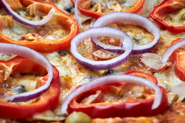 Domates soslu, mozarella peynirli, kırmızı dolma biberli, zeytinli ve mor soğanlı lezzetli ev yapımı pizza. Yakın plan..