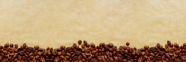 Kahverengi el işi kağıdında fotokopi alanı olan kavrulmuş kahve çekirdekleri. Uzun yatay afiş arkaplanı