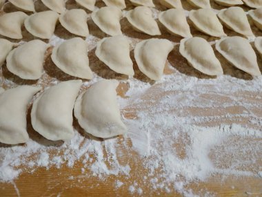 Ev yapımı hamur köfteleri un tozuyla kaplanmış ahşap bir masanın üzerinde yatıyor.. 