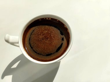 Beyaz arka planda sert gölgeli beyaz bir fincan kahve. 