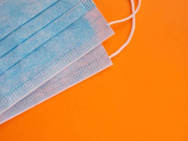 Turuncu arka planda tıbbi steril koruyucu mavi maskeler.