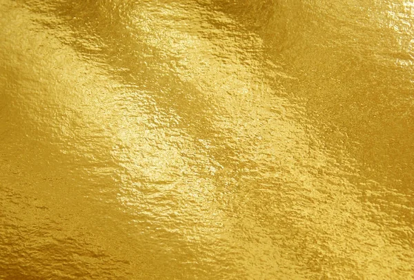 Gold foil texture background with highlights and uneven surface