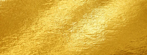 Gold foil texture background with highlights and uneven surface