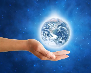 Mavi yıldızlı uzayın ortasında parlayan beyaz bir ışık halkası ile Dünya 'yı tutan kadın eli. Bu görüntünün elementleri NASA tarafından döşenmiştir.