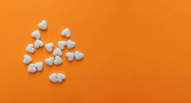 Turuncu arka planda kalp şeklinde beyaz haplar ve fotokopi alanı