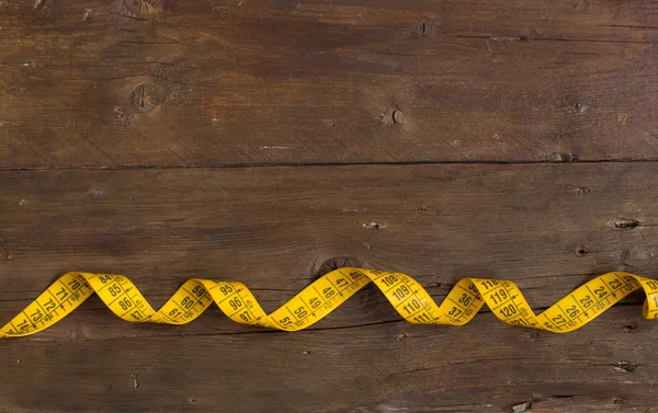Yellow measuring tape on wood — Stock Photo, Image