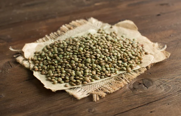 Pile de lentilles vertes sur une table en bois — Photo