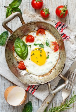 Sahanda yumurta domates ve otlar üzerinde eski bir kızartma tavası