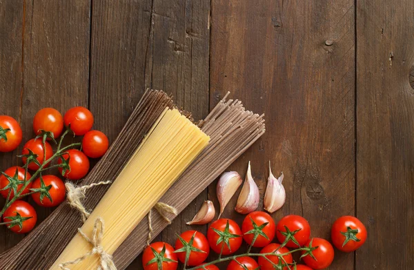 Three types of spaghetti, tomatoes and garlic — Stock Photo, Image