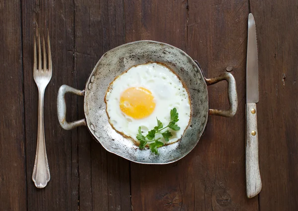 Жареное яйцо в старой сковороде с вилкой и ножом — стоковое фото