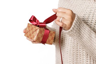 Genç kadın beyaza izole edilmiş bir hediye kutusunu çözüyor.