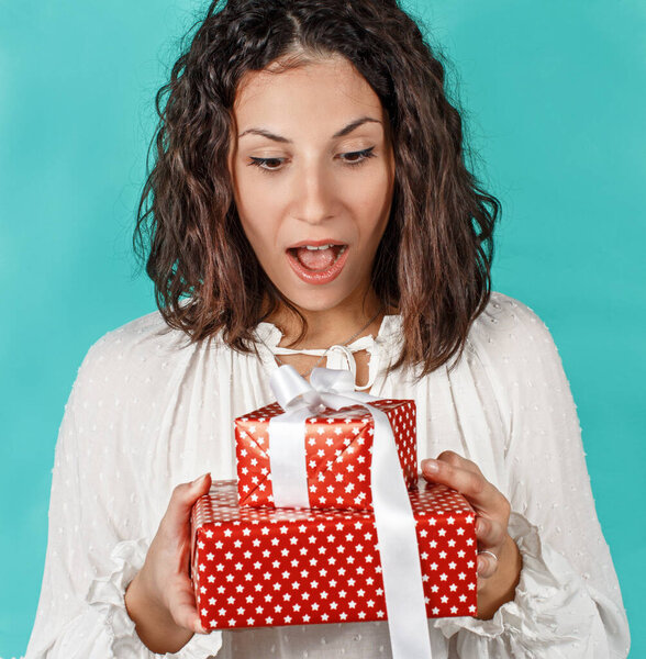 Surprised young woman holding Gifts in hands isolated on green