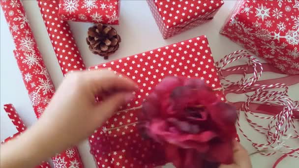 Woman attach a decorative flower to gift wrapped present — Stock Video
