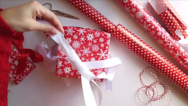 Женщина завязывает ленту бантом и упаковывает подарки — стоковое видео