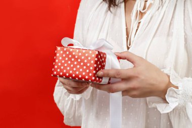 Elinde hediye paketi tutan genç bir kadın. Kırmızıya yakın bir yerde.