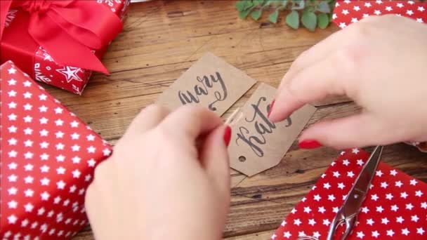 Mãos anexando etiqueta de presente ao presente de Natal — Vídeo de Stock