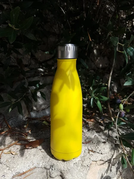 Yellow reusable steel bottle in nature  close up