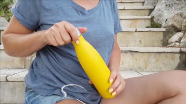 Kadınların yakınına, sarı, yeniden kullanılabilir çelik şişe açıyorlar.