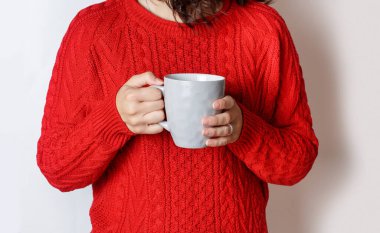 Kırmızılı bir kadının gri fincanda gri çay tutarken görüntüsü.