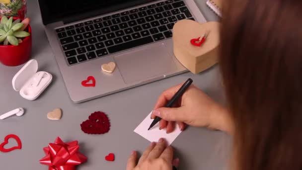 Giovane donna che scrive un biglietto ti amo e che avvolge il regalo di San Valentino — Video Stock