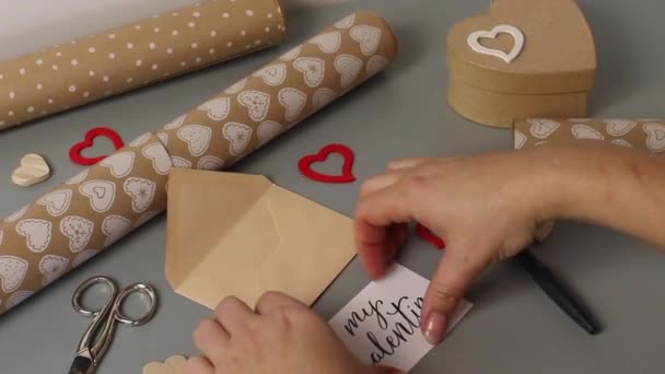 Seseorang menaruh kartu tulisan tangan BE MY VALENTINE ke dalam amplop. Membungkus valentine hadiah hari — Stok Video