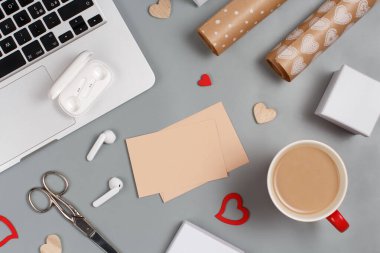 Bir fincan kahve, Hearts, laptop, kulaklıklar, makas, hediye kutuları ve hediye kağıdı üst görünümü. Sevgililer Günü konsepti