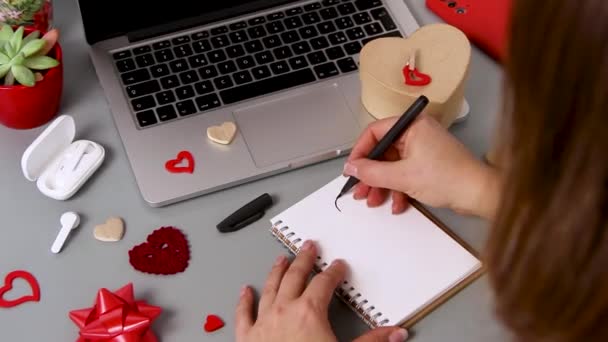 Νεαρή Γυναίκα Ζωγραφίζει Μια Καρδιά Ένα Σημειωματάριο Ενώ Τυλίγει Δώρο — Αρχείο Βίντεο
