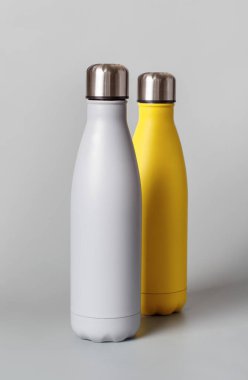 Gri arka planda gri ve sarı yeniden kullanılabilir şişeler yakın plan. Sıfır atık, plastiksiz ve sürdürülebilir yaşam tarzı kavramı