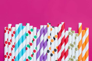 Çizgili ve noktalı kağıt, pembe arka plan manzarasında pipet içiyor. Çevre dostu kavram