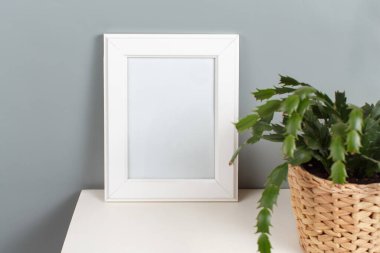 Beyaz poster çerçeve ön görünüm Gri wal üzerinde bir saksı bitki ile