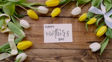 Kart başında laleler Mutlu Anneler Günü 'nü tahta bir masanın üstüne koyun. 