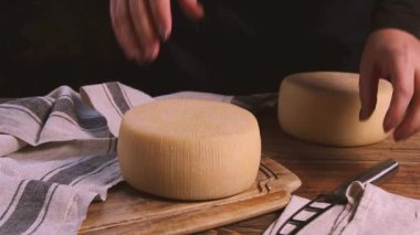 Kadınlar ahşap bir tahtanın üzerinde taze ev yapımı bir peynir çarkını yakın mesafeden peynir bıçağıyla kestiler.