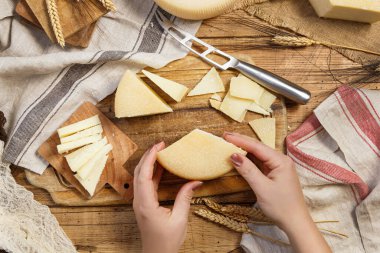 Eller ahşap bir tahtanın üstünde taze ev yapımı peynir parçaları tutuyor.