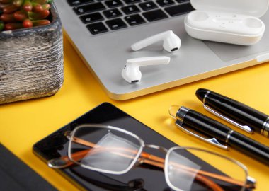 Sarı arka planda cep telefonu ve modern cihazlar var. İş konsepti