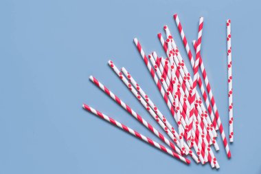 Çizgili ve noktalı kağıt açık mavi arkaplan görünümünde pipet içiyor