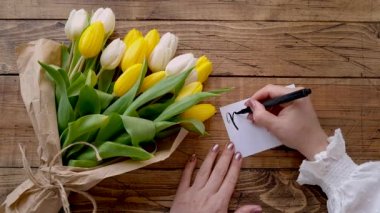 Kart Anneler Günü 'nü lale buketinin yanındaki ahşap masaya yazmak. 