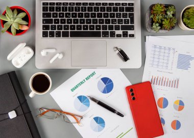 Rapor veren ofis masası, dizüstü bilgisayar ve kahve fincanı manzaralı modern cihazlar.