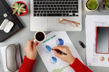 Kadın elleri rapor yazıyor ve laptopun yanında kahve içiyor.