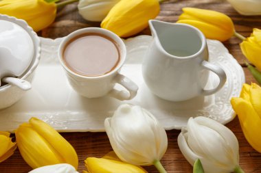 Tahta masadaki beyaz ve sarı laleler arasındaki sehpayı kapat. 