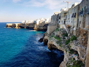 Polignano ve Mare deniz kıyısından mavi deniz manzarası. İtalya 'nın Apulia kentindeki Adriyatik Denizi üzerinde kumtaşı uçurumlarının kenarına kurulmuş manzaralı bir kasaba.
