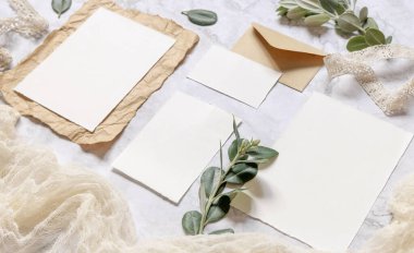 Üzerinde okaliptüs dalları ve kurdelelerle süslenmiş mermer bir masa bulunan düğün kağıtları. Boş kağıt tebrik kartlarının olduğu bir sahne. Kadınsı yakın çekim