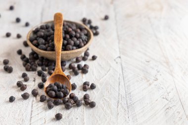 İtalya 'daki Apulia ve Basilicata' dan gelen seramik kase dolusu siyah nohut gri masa ve kaşık üzerinde fotokopi alanı, yakın plan.
