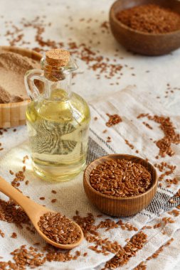 Çiğ keten tohumu unu, yağ ve tohumları beyaz masaya yakın bir kaşıkla.