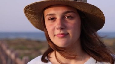 Hasır şapkalı genç kız deniz kenarında yürüyor. 