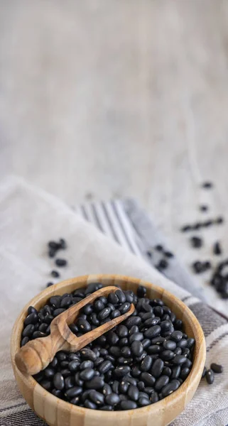 Ahşap Bir Kâse Dolusu Kuru Siyah Fasulye Mutfak Havlularının Üzerinde — Stok fotoğraf