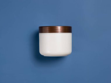 Mavi arka plan manzaralı kahverengi kapaklı krema boş kavanozu. Kozmetik krem maketi