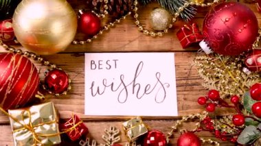 Üzerinde el yazısıyla yazılmış en iyi dilekler yazılı kart ahşap masanın üzerinde Noel süslemeleri üst görünümde yakınlaştır