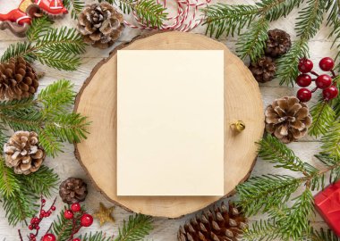 Kış Noel Kompozisyonu ve tahta masa üzerinde boş bir kart. Noel ve Yeni Yıl tebrik kartı şablonu köknar ağacı dalları, çam kozalakları ve süslemelerle dolu. Tatil modeli..